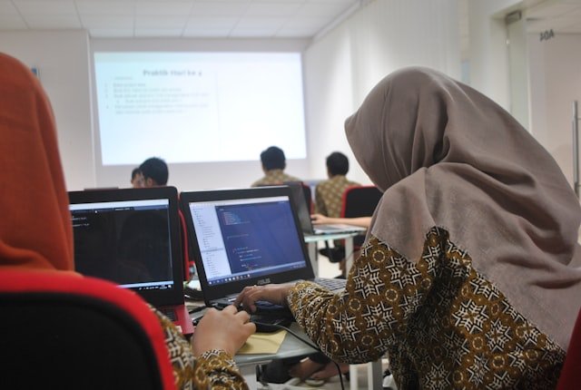 woman wearing grey hijab using laptop compiter