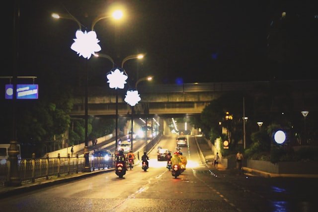 a group of people riding motorcycles down a street at night